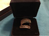 Two rings in open black jewelry box on blue background