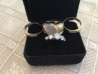 Four rings displayed together in black presentation box on patterned surface