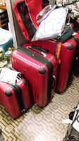 Front view of three nested red hard shell suitcases showing handles and corner bumpers