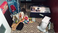 Photo of assorted items including books, cane, ObusForme seat back, Invacare Comfort Mate Extra padded seat, and Easy Cycle box and device on patterned carpet.