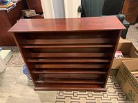 Front view of wooden shoe rack showing four open shelves