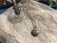Overview of four rings displayed on crystal ring holder alongside chain and locket pendant on tissue