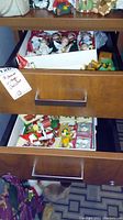 Drawer partially opened revealing more assorted Christmas wood and ceramic figurines packed inside.