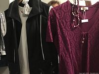 Black zip-up jacket with white piping and burgundy lace top with matching necklace.