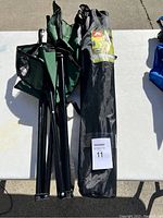 Two folded green camping chairs and one black carrying bag placed on a white table surface.