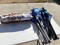 Two camping chairs folded and leaning on a table along with the portable sunshade in its carrying bag.