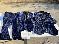 Three-piece blue floral patterned suit including jacket, vest, and pants laid out on a table.