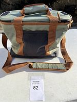 Front angled view of insulated cooler bag with handles, shoulder strap laid out in front, and MaxSold lot card in front.