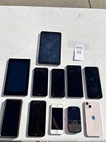 Image showing 10 cell phones and tablets laid out on a white surface, several with cracked screens.