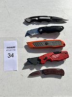 All five cutting tools arranged in a row showing different styles: folding knives, utility knives, and pocket knife.
