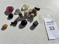 Photo showing the full assortment of gems and rare stones including tumbled stones, a vial of amethyst, and a white crystalline geode.