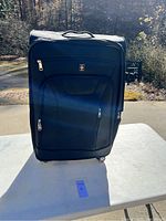 Front view of large black suitcase with multiple zippered compartments and Swiss red cross emblem visible.