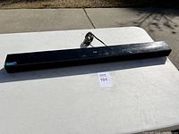 Full view of the black LG soundbar placed on a white table outdoors.