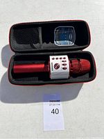 Red Bonaok wireless handheld microphone inside zippered semi-hard carrying case with mesh pocket in lid.