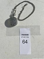 Silver pocket watch with decorative case and attached chain against a white background.