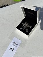 Silver necklace inside a white Pandora box on a white surface, necklace chain loosely arranged inside the box.