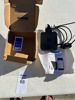 Overview of hardware components, box, manual, and small electronic device.