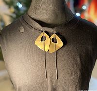 Photo of earrings on a black mannequin bust showing full front view including the asymmetrical brushed metal diamond shapes with square cut outs and the oxidized chain drops.