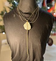 Front view of the necklace on a display monoform with the pendant centered and chains layered.