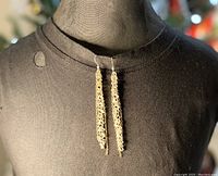 Front view of long layered silver plated cluster chain earrings with thin gold plated chains interwoven, hanging from silver plated ear wires, displayed on black mannequin bust.