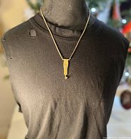 Full front view of necklace worn on mannequin with brass snake-shaped pendant and crystal drop on brass chain.