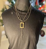 Necklace displayed on a black mannequin bust, showing full chain and pendant length with twisted rope chain and double rectangular pendant with hanging bar.