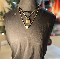 Front full view of the necklace on a mannequin showing double chains with pewter heart pendant and brass lock
