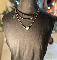 Full view of pendant necklace displayed on bust, showing double vintage brass chain and pewter heart pendant.