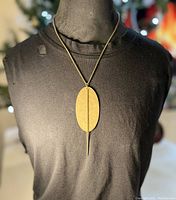 Full view of necklace with brass hammered oval pendant on black mannequin