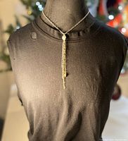 Front view of necklace on mannequin showing the white agate skull pendant and mixed metal tassels hanging down on silver chain.