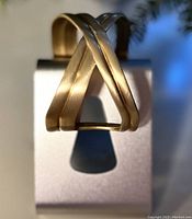 Close-up photo of the hand brushed solid brass X wrist cuff showing the brushed texture and X design shape.