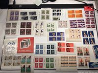 Top view of a large assortment of new Canadian postage stamps arranged flat, showing a diverse selection of sheetlets and blocks in various colors and denominations.