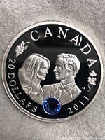 Obverse side of the coin showing Prince William and Kate Middleton portraits with a blue gemstone embedded near bottom center, inscriptions 'CANADA', '20 DOLLARS', and '2011'.