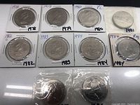 Full lot of 10 Canadian $1 coins from 1978-1986, displayed in protective sleeves with handwritten year labels.