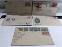 Photo showing all five First Day Cover envelopes arranged side by side on white surface.