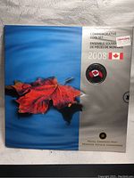 Front of sealed Royal Canadian Mint 2008 commemorative coin set packaging showing design with a vibrant maple leaf on a blue and silver background with the Canadian flag and year '2008'.