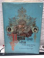 Cover of the hardcover book with decorative blue textured surface, Cyrillic and English titles, and artistic illustrations including a knight on horseback and portraits.