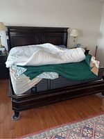 Full view of bed frame with mattress on it, showing dark wood frame and legs.