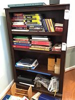 Front view of brown wooden bookcase filled with books and various items, showing scratches on surface.