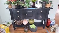 Front view of black Broyhill buffet with drawer, cabinet, and open shelf storage, holding decorative pottery items (not included).