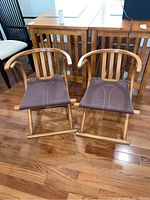 Front view of both chairs showing canvas seats and curved wooden frames