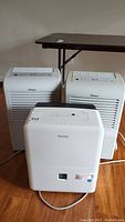Front and top views showing three white portable dehumidifiers; one Danby and two Danby Premier units with control panels visible.