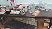 Full view of wooden dining table with various household items placed on top, showing table size and general appearance.