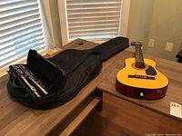 Photo showing the Hohner kids guitar placed on a table next to a black soft case containing the Firstact flute.