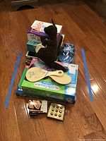 Photo showing stacked board games: Taboo on top, LeapPad LittleTouch box at the bottom, brown plush kangaroo on top, two wooden paddles of paddle ball, and some small card game boxes.