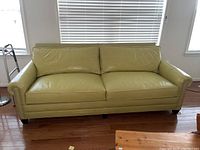 Front view of the chartreuse leather sofa showing two-seat configuration and nailhead trim