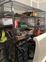 Photo of metal wire shelving unit in garage/storage with various boxes and items on shelves. Shows overall structure and contents to demonstrate shelf size and usage.