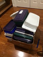 Stack of assorted plastic storage bins and lids in various colors, showing quantity and color variety.