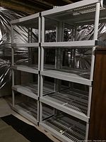 Front view of two linked gray plastic shelving units showing all four tiers and tubular support posts.