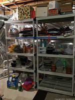 Two assembled grey plastic shelving units side by side with various items on shelves